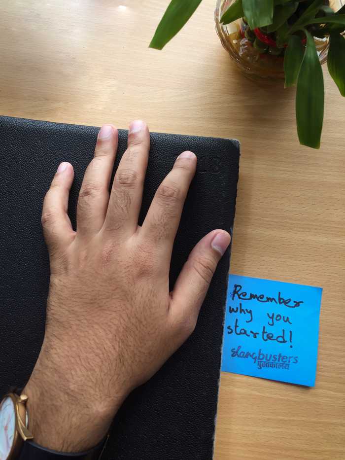 Hand on a diary next to a note saying remember why you started