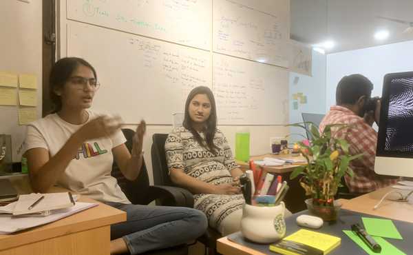 2 slangbusters sitting on the corner of the studio with one explaining and one smiling
