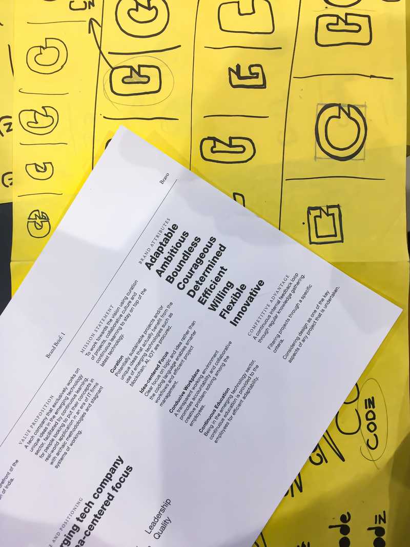 Sheets of paper with brand brief and some brandmark iterations